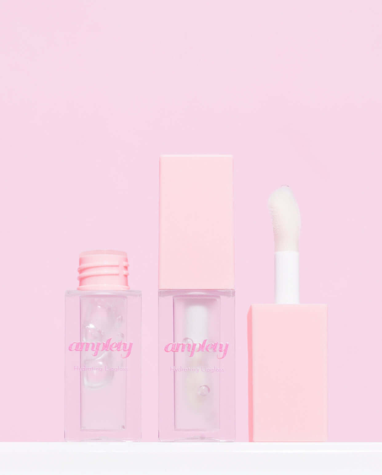 Three stylish peppermint lipgloss tubes with pink packaging against a soft pink background.